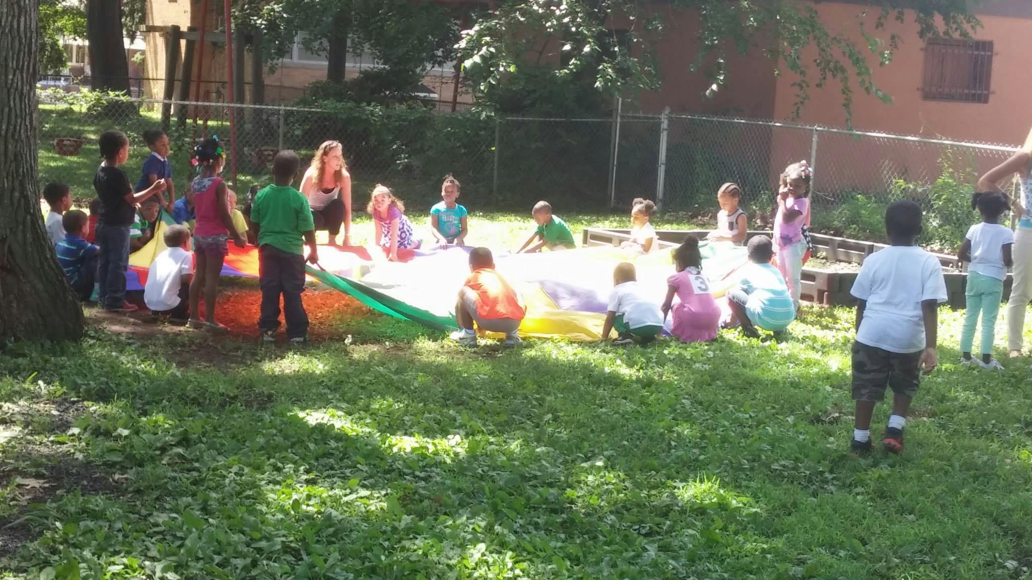 Children and an adult playing with a colorful parachute outdoors