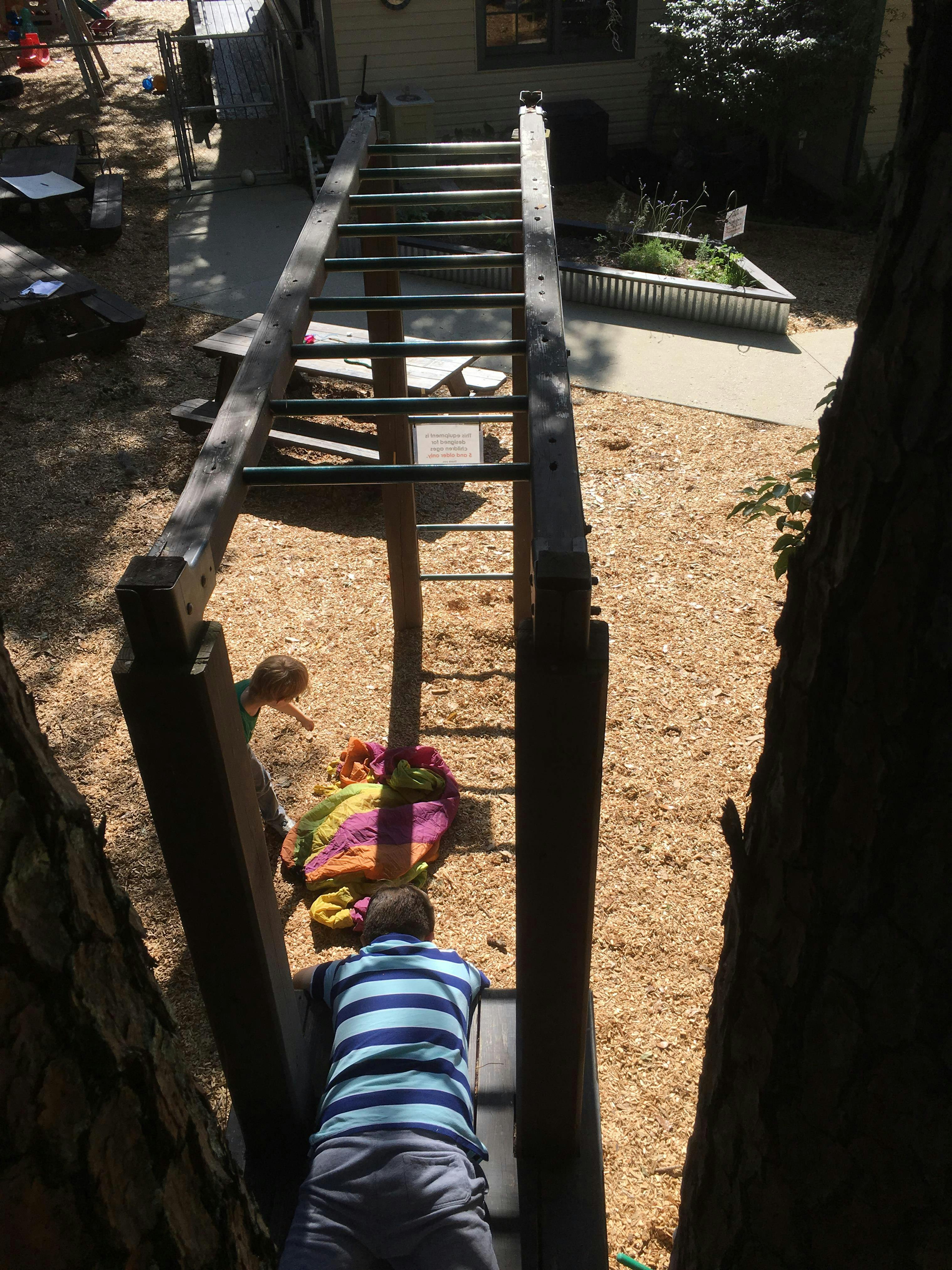 Child climbing a ladder, another child nearby