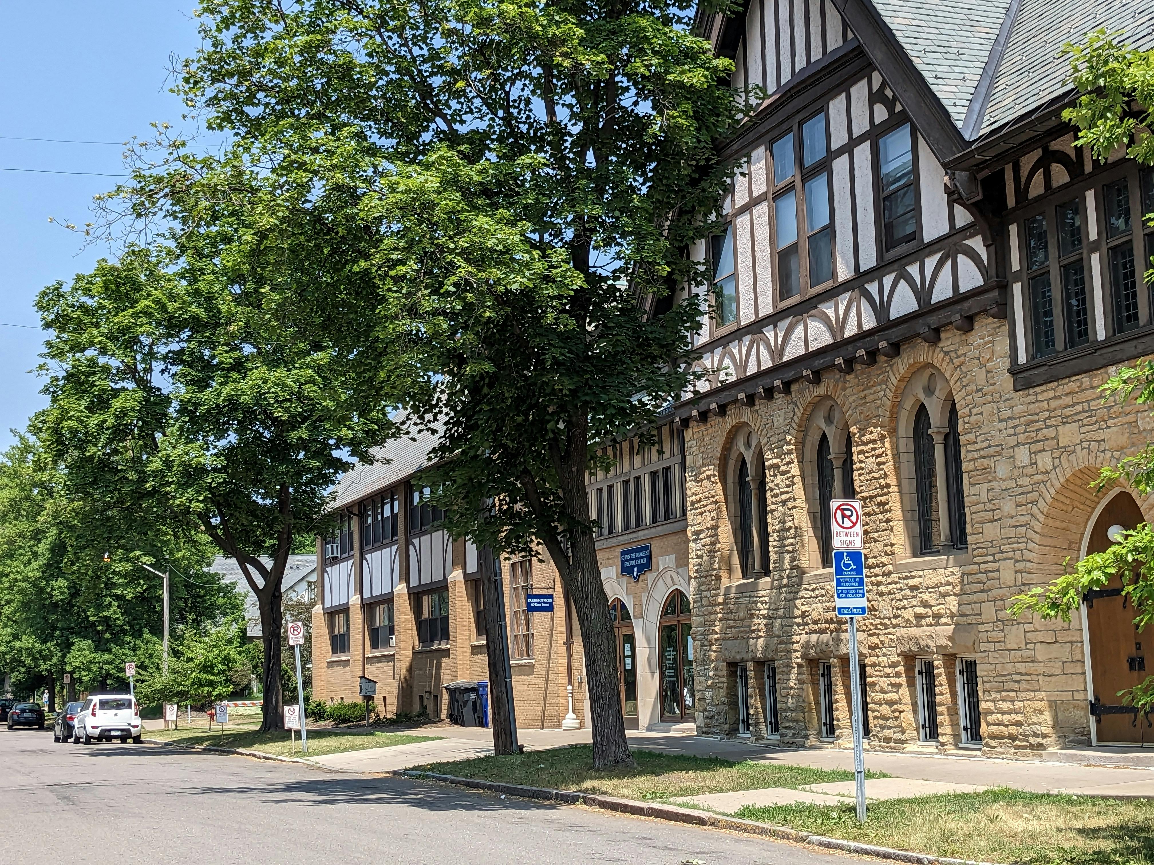 Street view of a stone building with arched windows and a timber-framed upper story