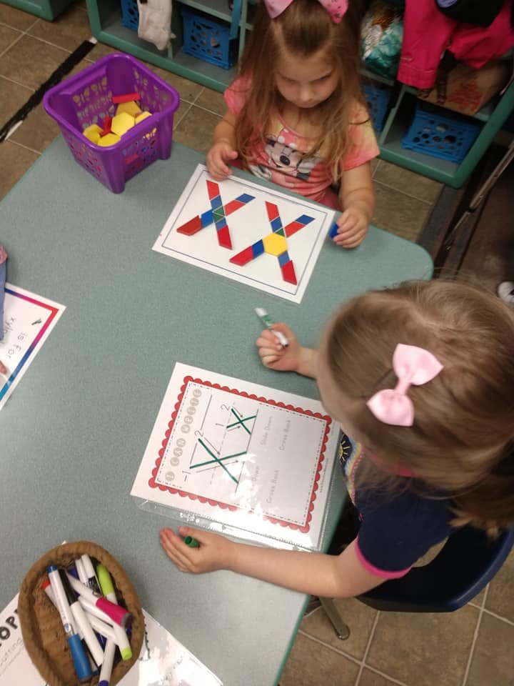 Two children at a table working on learning activities
