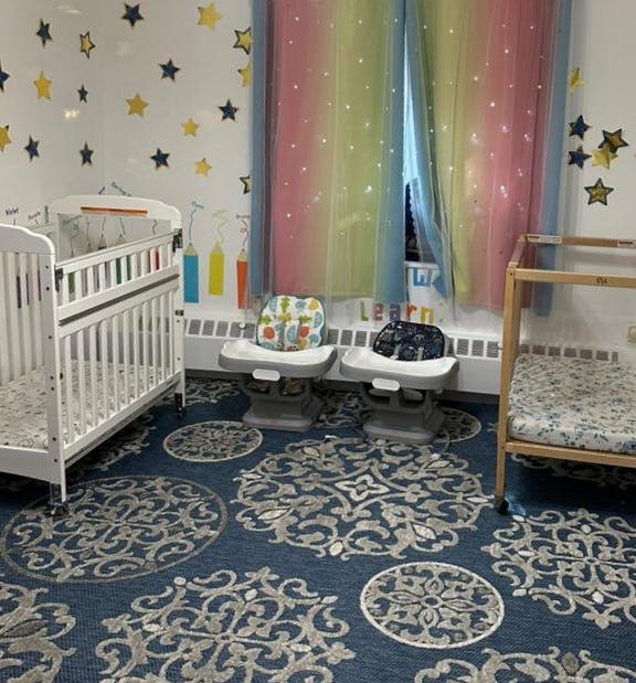 Nursery room with cribs, high chairs, and star decals on the wall
