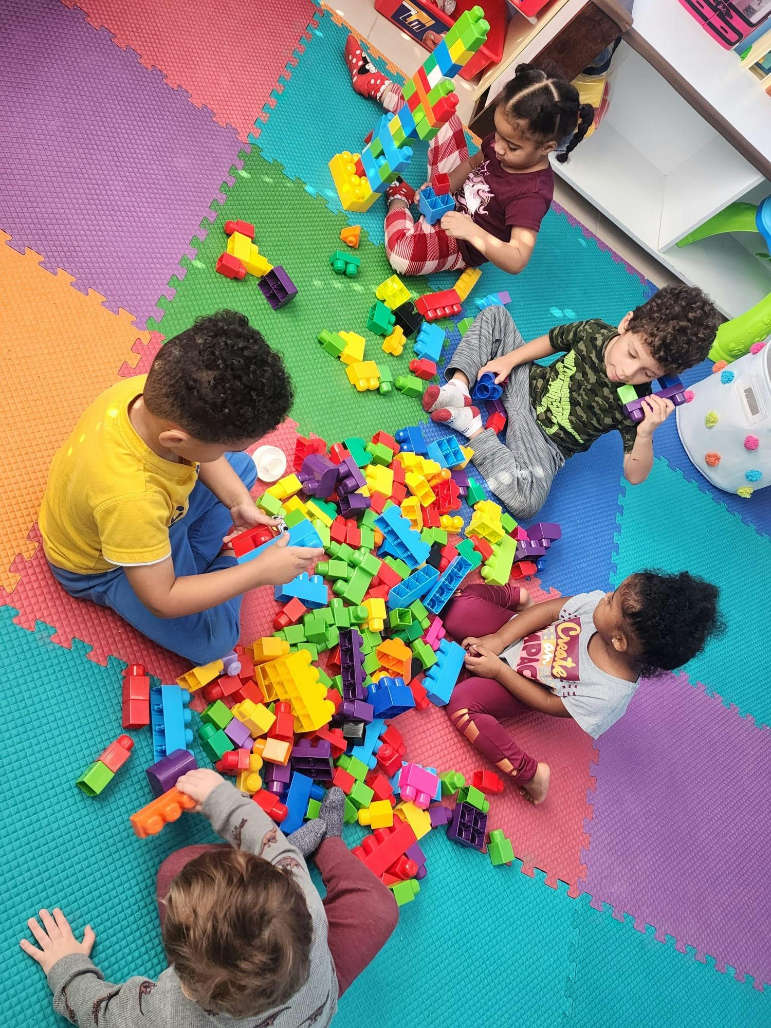 Children playing with colorful building blocks on a mat