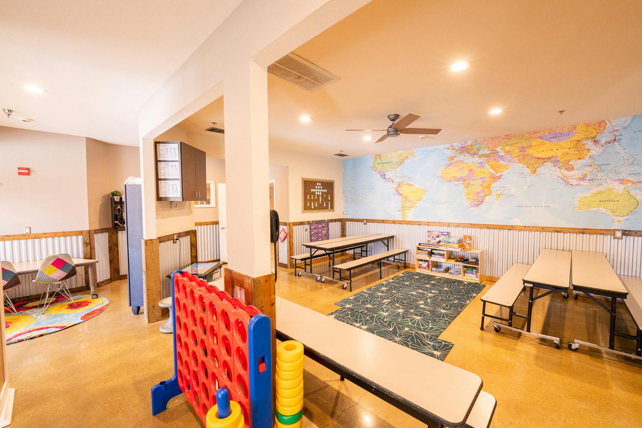 Multipurpose room with tables, benches, games, and a large wall map