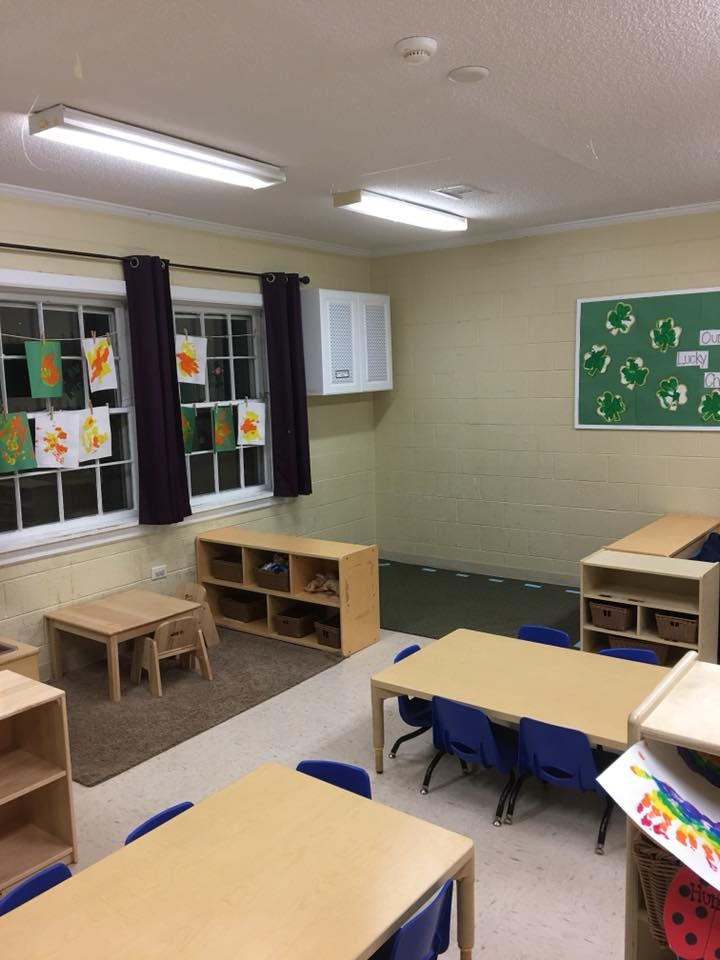 Classroom with small tables, chairs, and artwork in windows