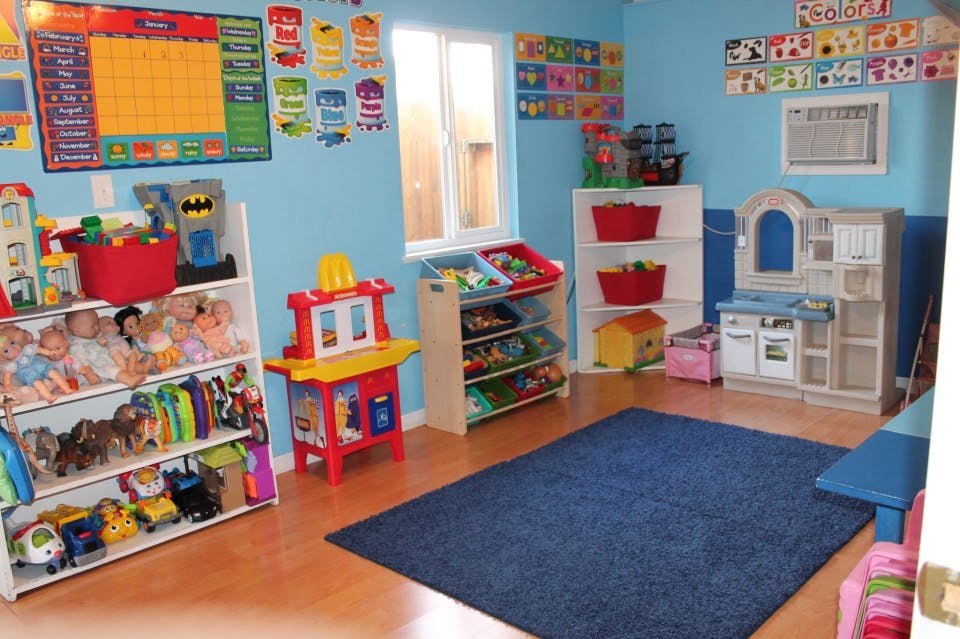 Playroom with shelves of toys, a play kitchen, and a blue rug