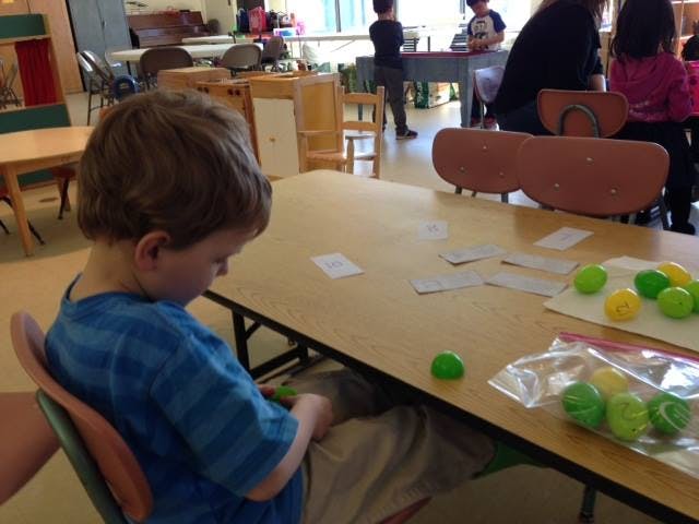 Child sitting at a table with plastic eggs and cards