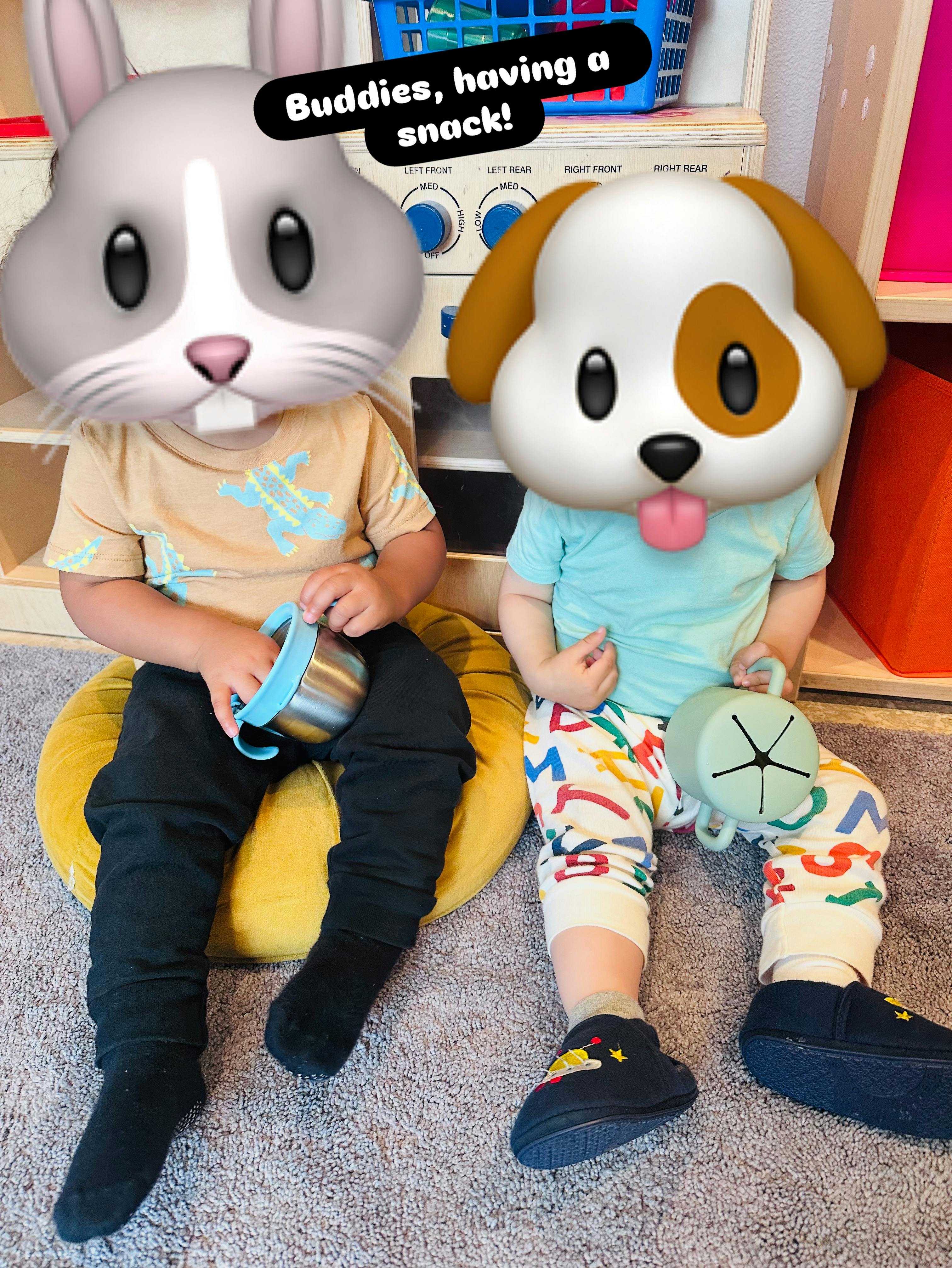 Two children with animal emoji faces holding snack cups