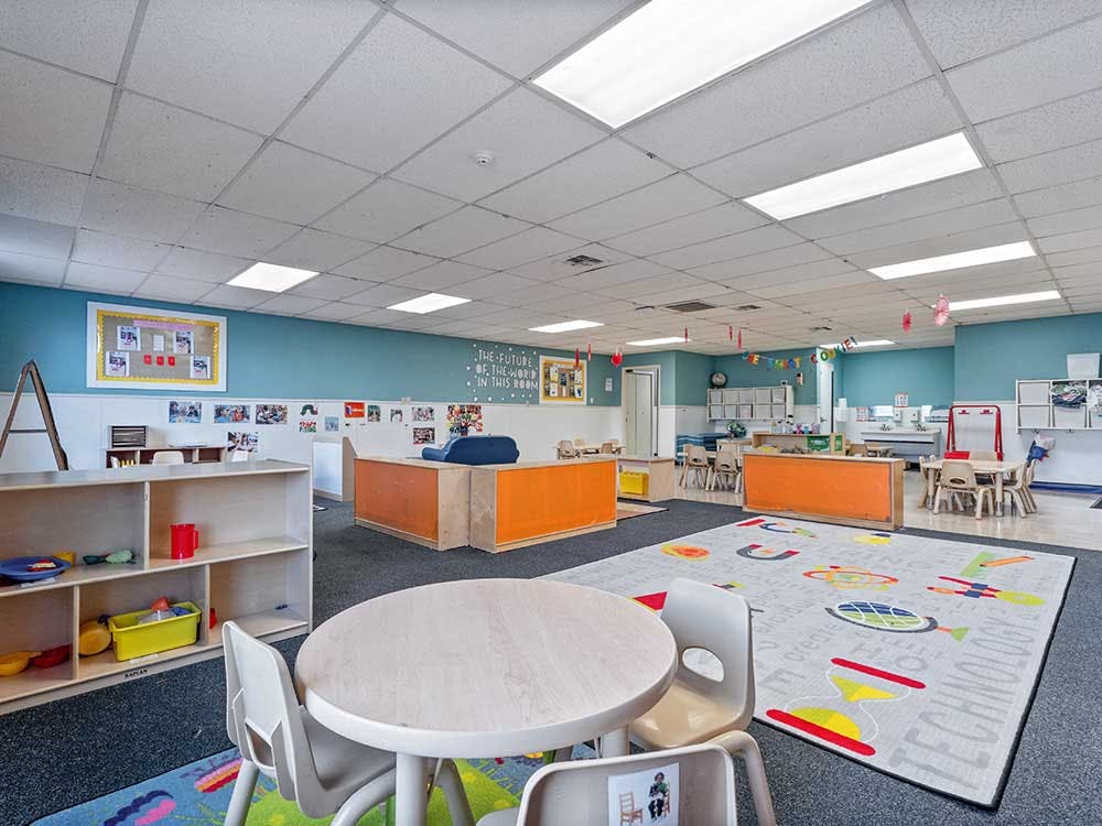 Empty classroom with small tables, chairs, and shelves