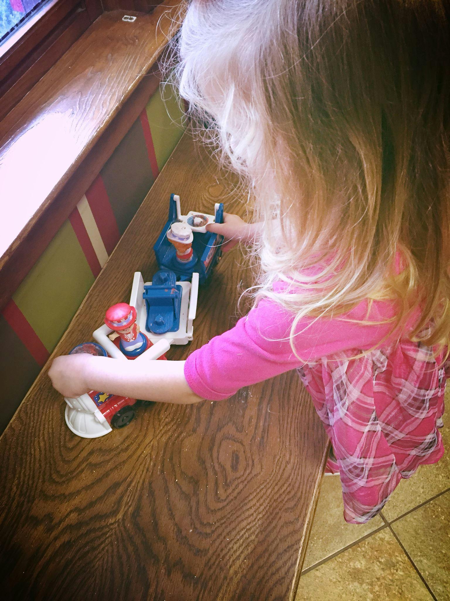 Child playing with toy vehicles on a wooden surface