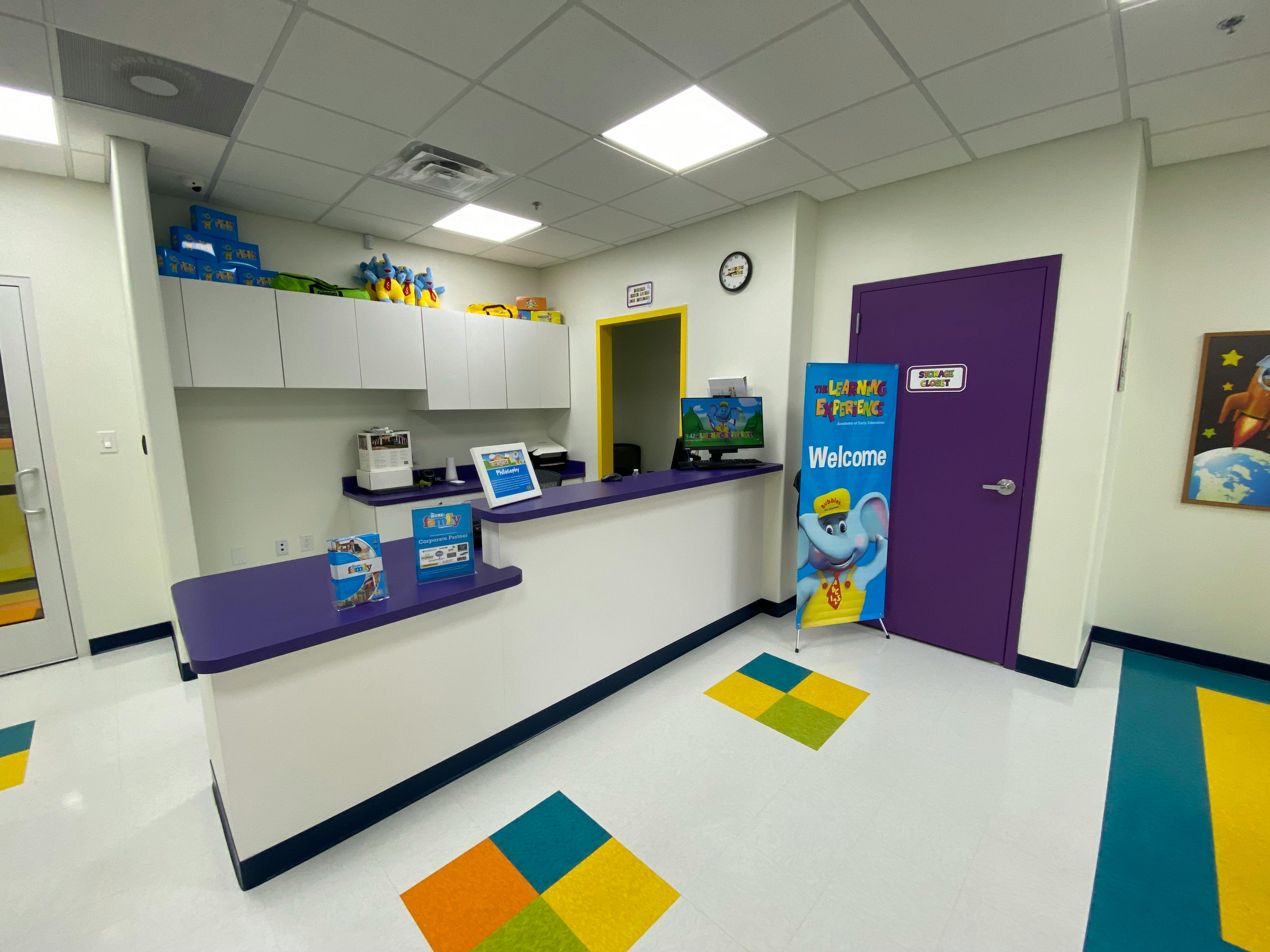 Reception desk with a welcome sign and purple door