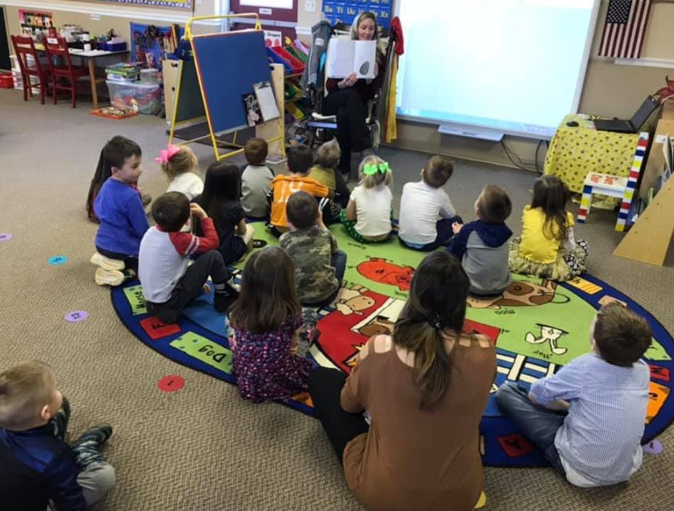 Person reading to children sitting on a rug in a classroom