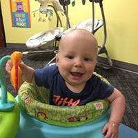 Child in a baby seat holding a toy