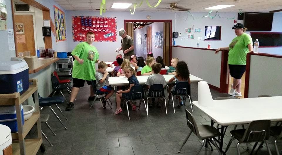 Adults and children in a room with tables and chairs