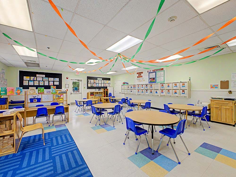 Empty classroom with small tables and chairs, colorful streamers
