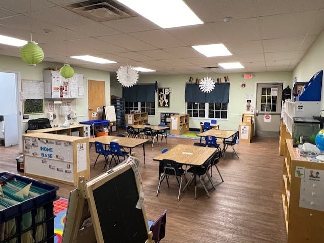 Empty classroom with small tables and chairs, and learning materials