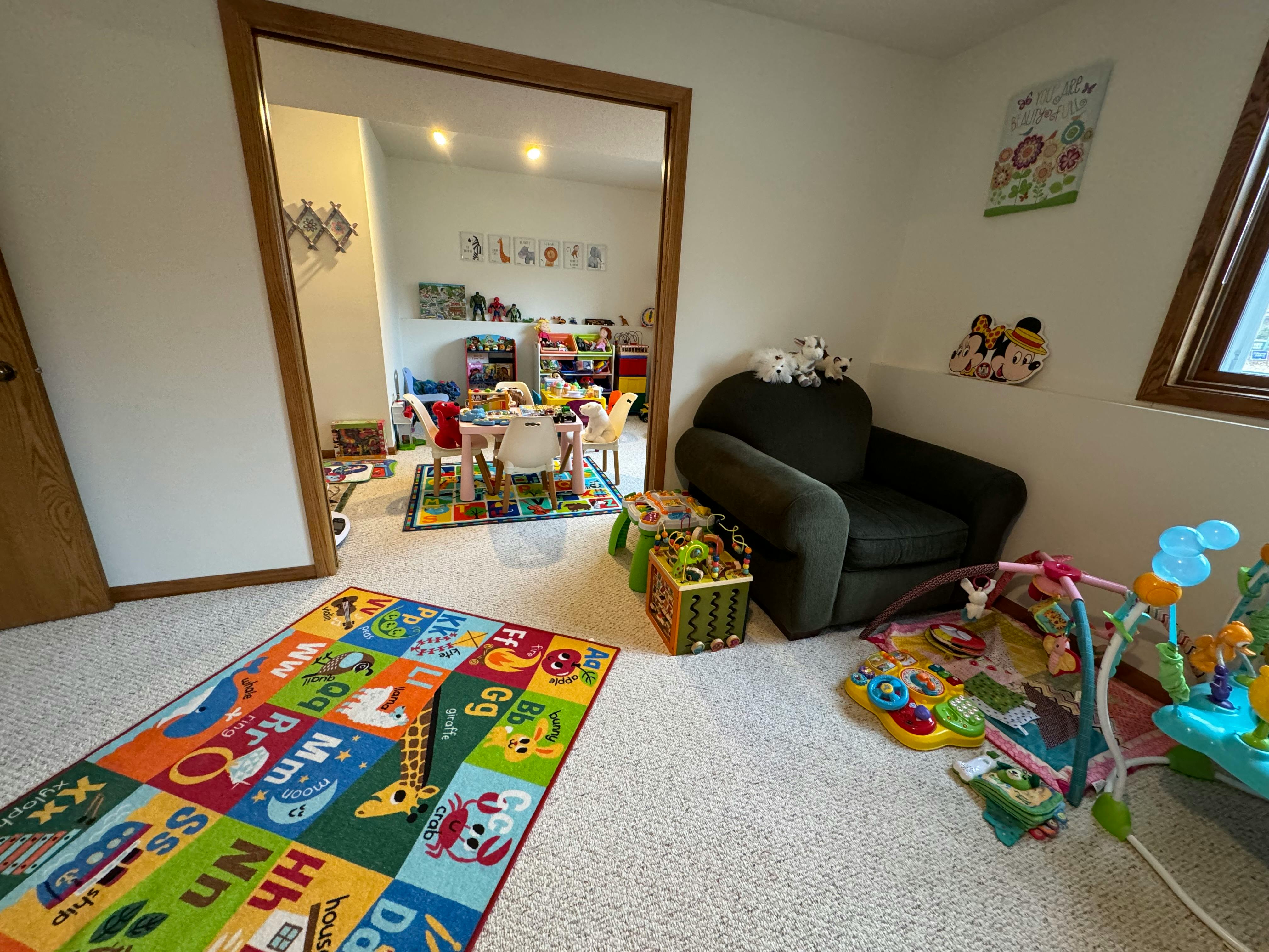 Playroom with a colorful alphabet rug, armchair, and baby activity toys