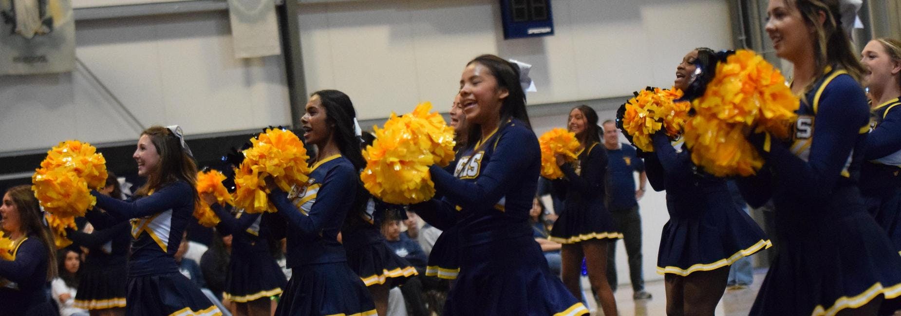 Group of cheerleaders holding yellow pom-poms during a performance