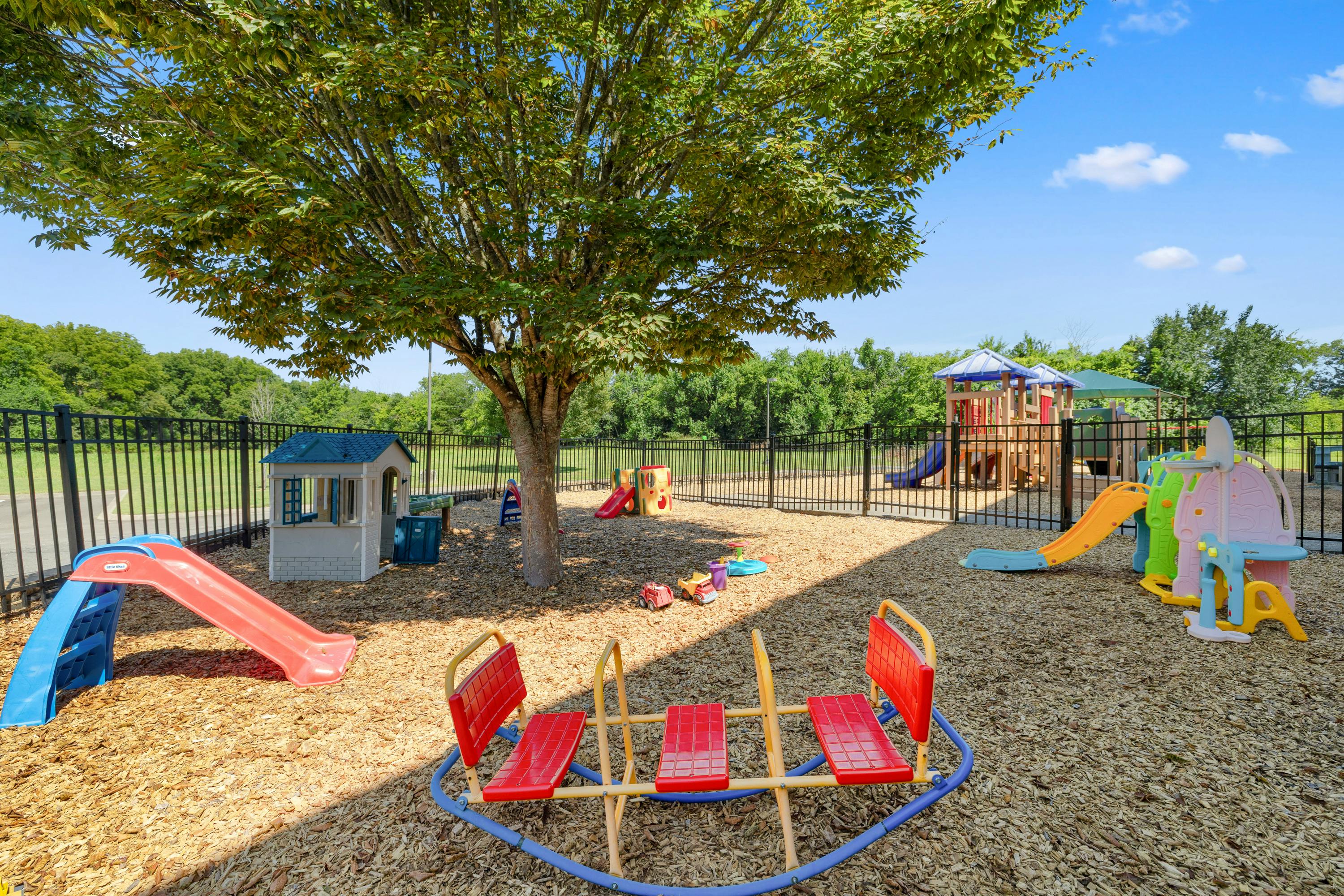Playground with slides, a playhouse, and a seesaw on wood chips
