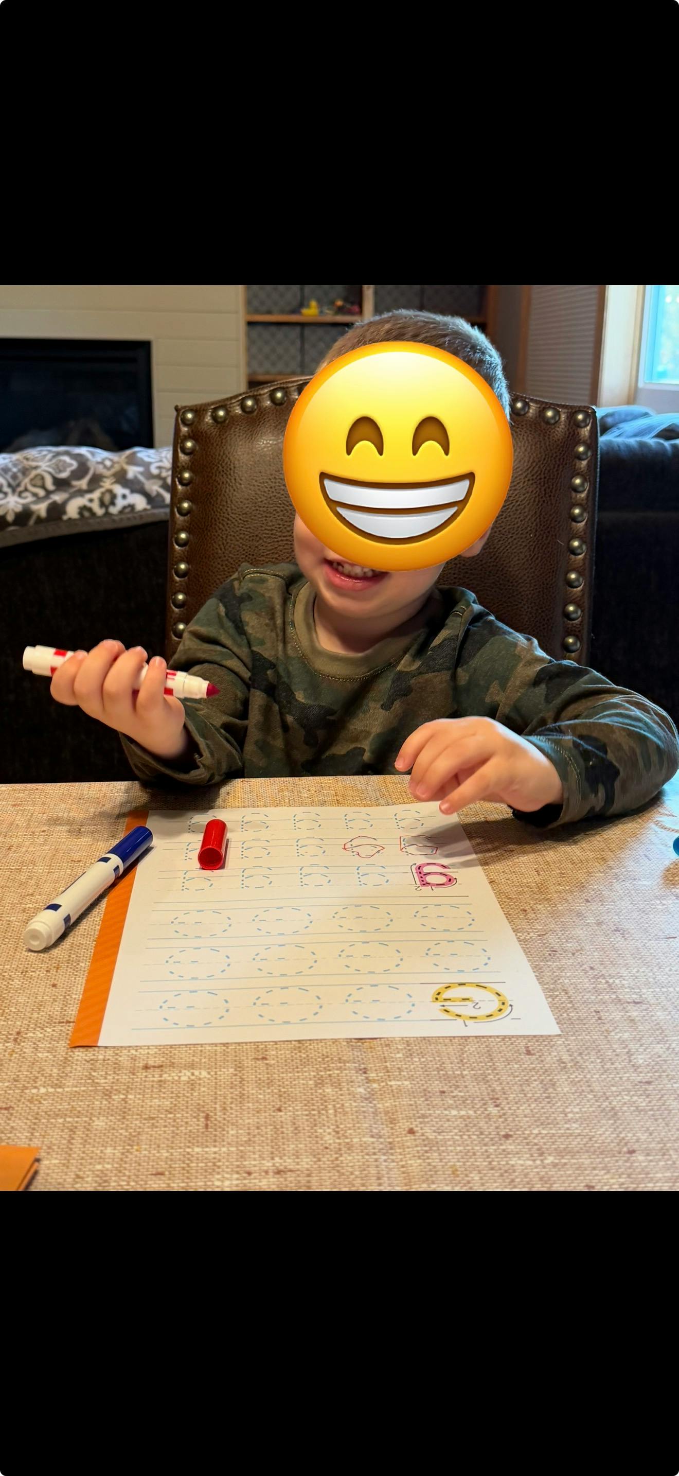 Child practicing writing on a worksheet with markers