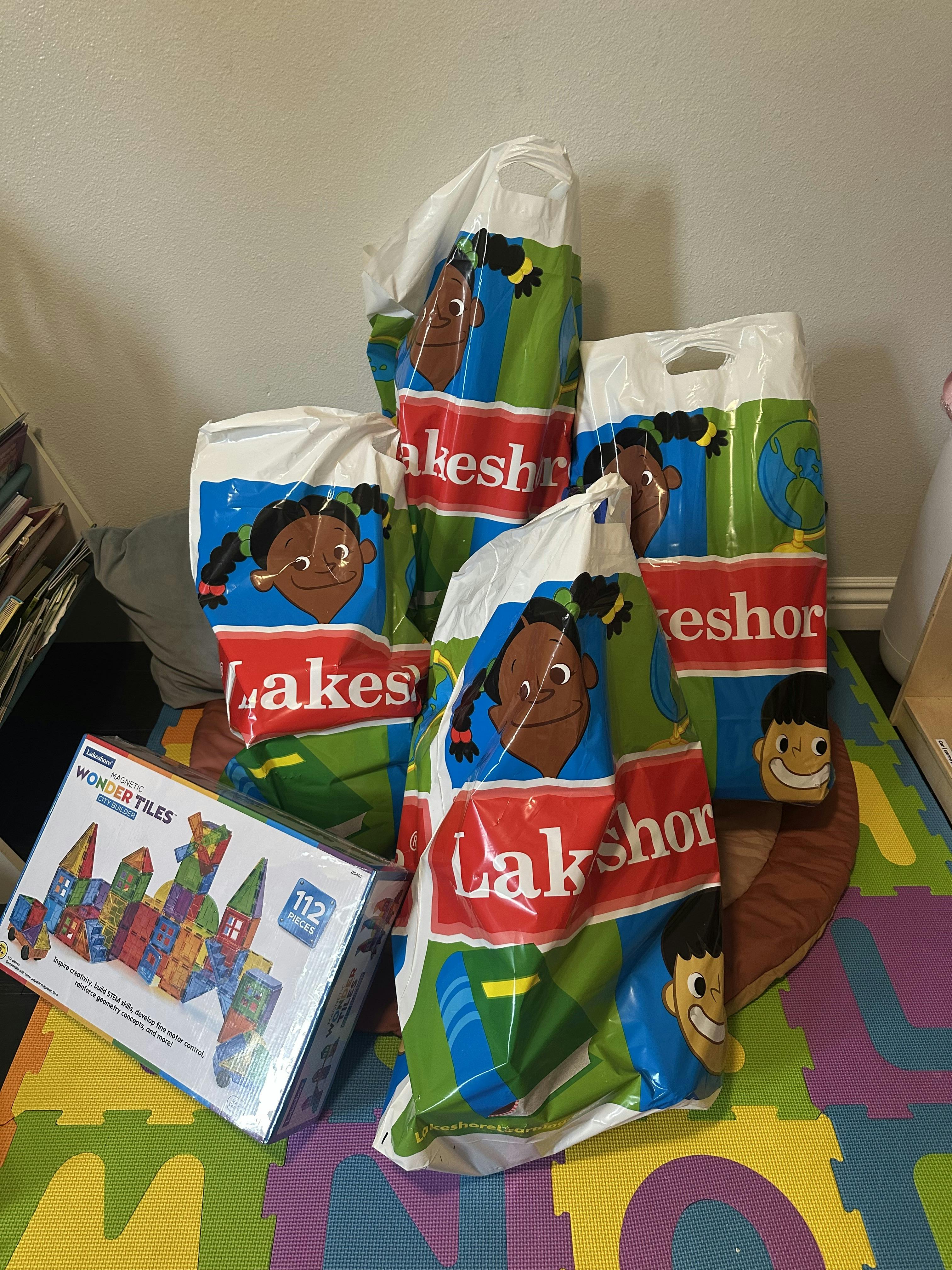 Lakeshore shopping bags and a box of magnetic building tiles on a play mat