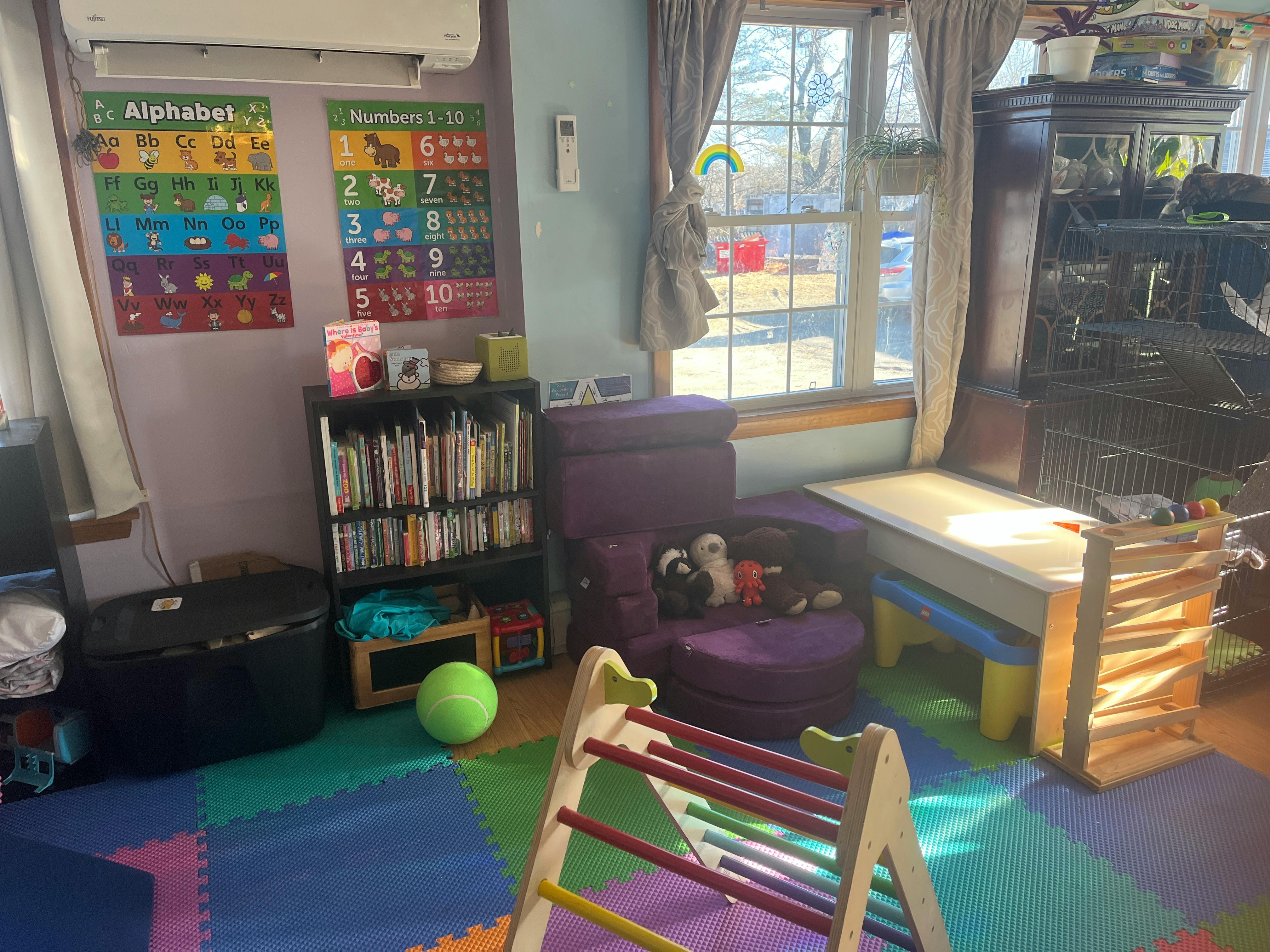 Playroom with colorful floor mats, a bookshelf, and a small slide