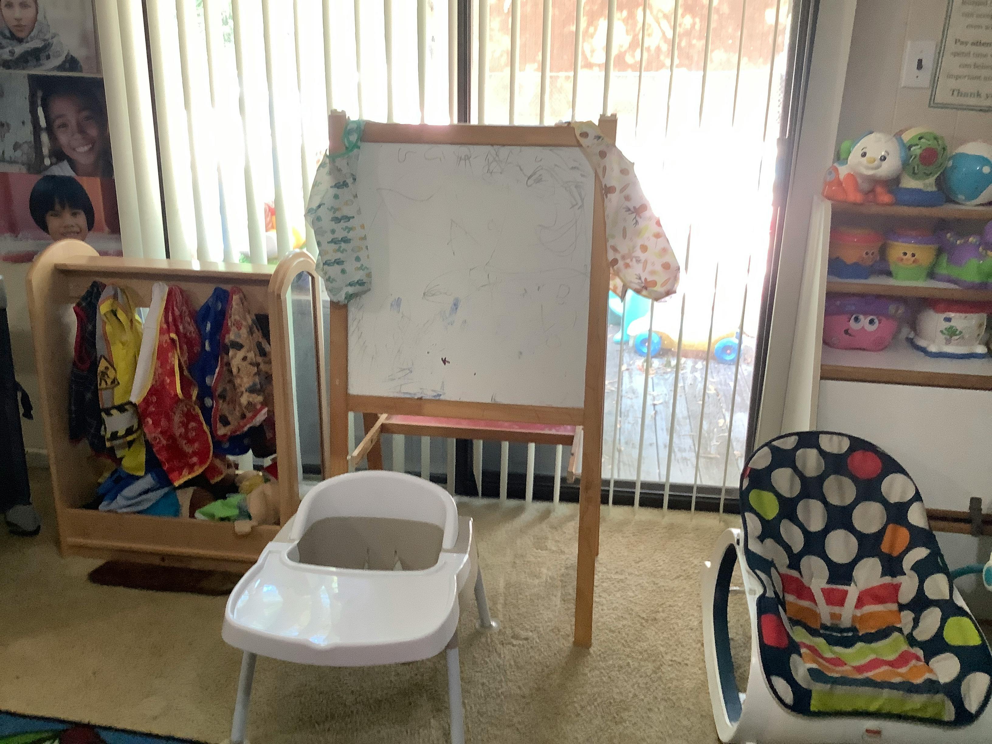 Child's high chair, easel, and clothing rack in a room