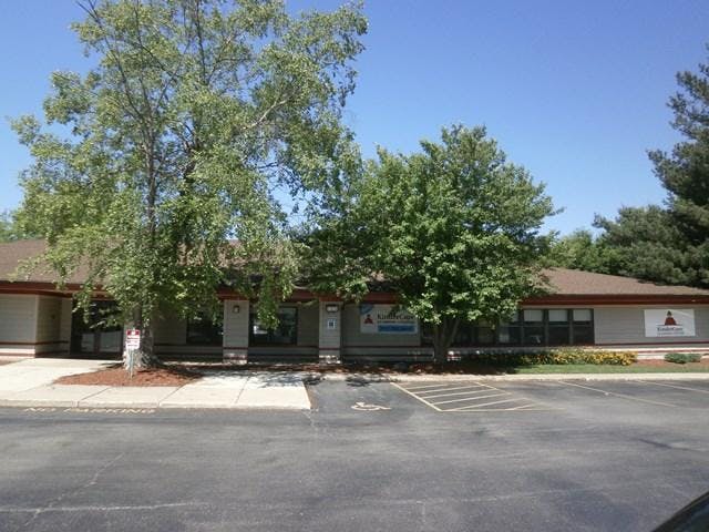 Building with "KinderCare" signs and a parking lot with trees