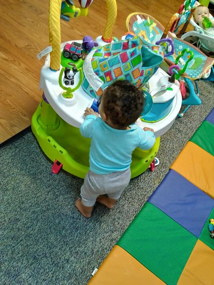Child standing at a baby activity center
