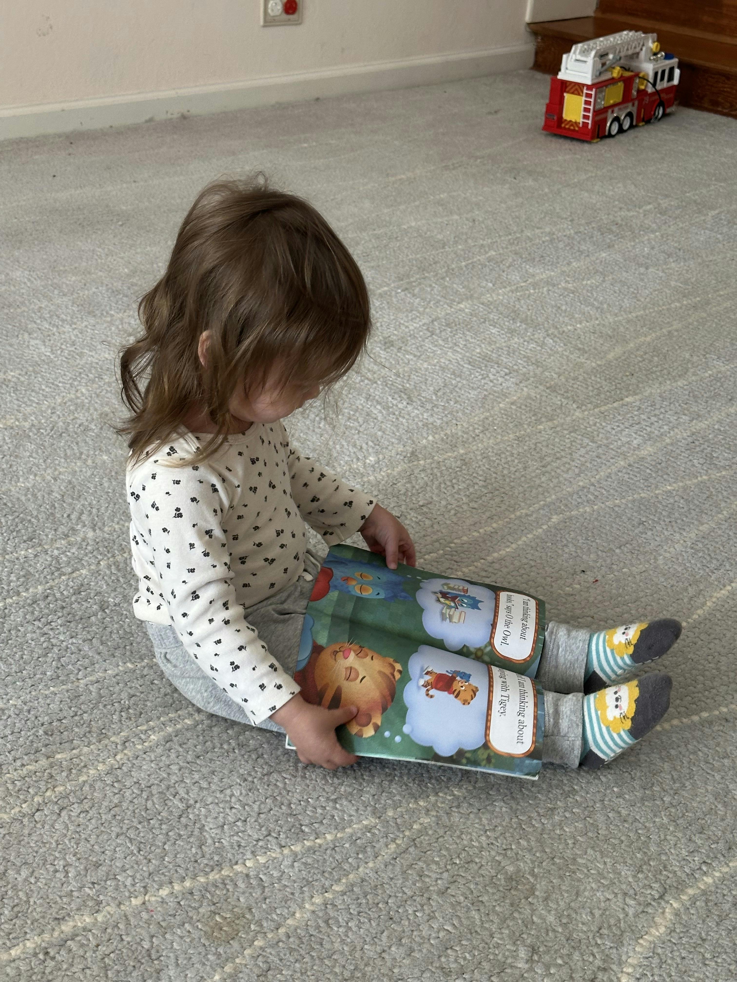 Child sitting on floor reading a book with cartoon animals