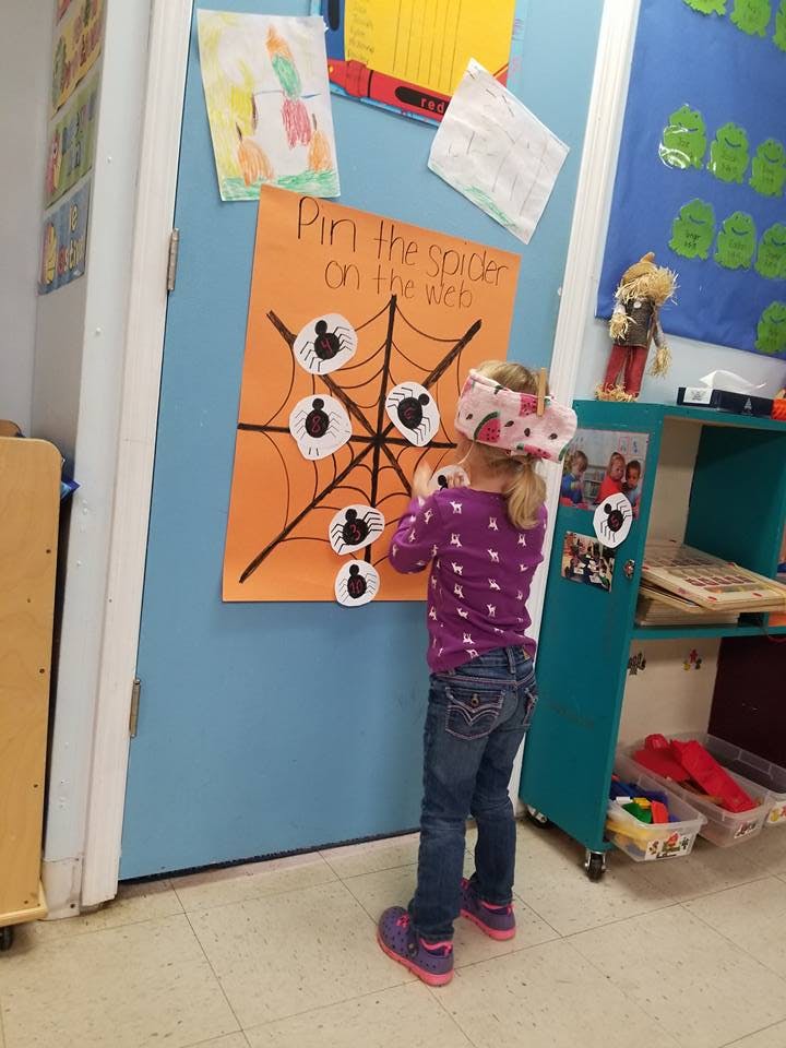 Child playing "Pin the Spider on the Web" game
