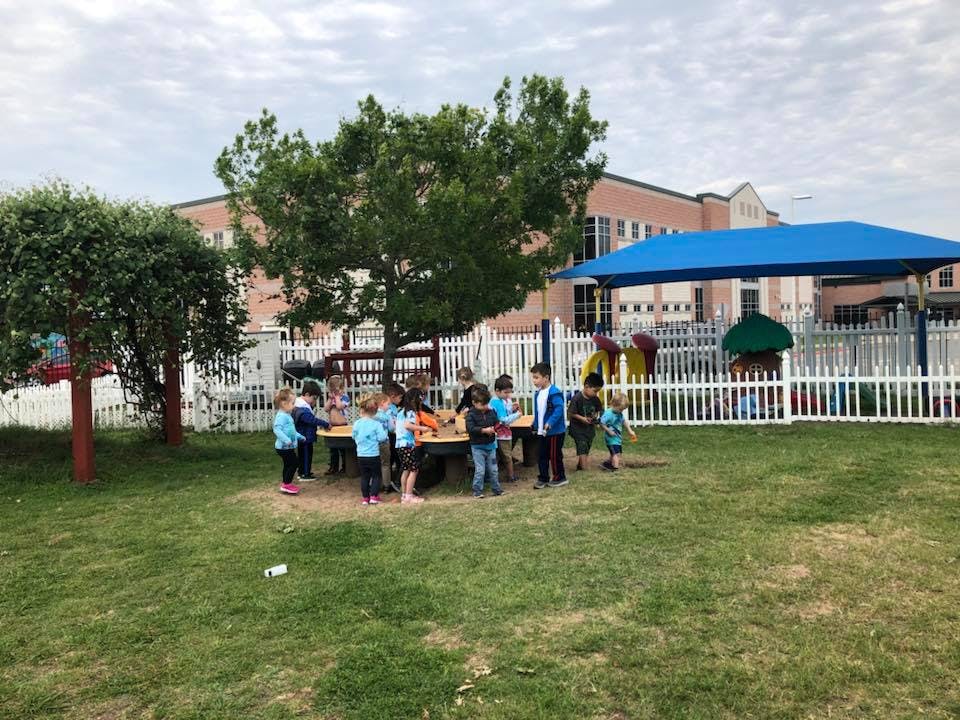 Children gathered around a table outdoors on a grassy area