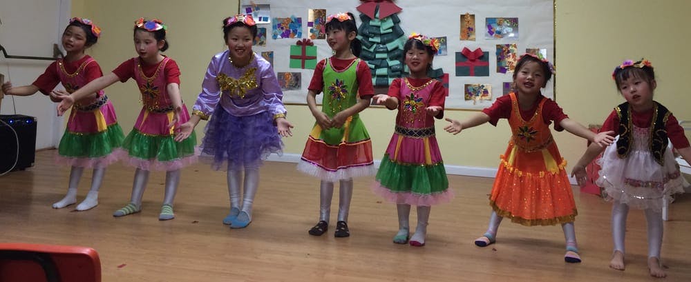 Seven children in colorful dresses performing a dance