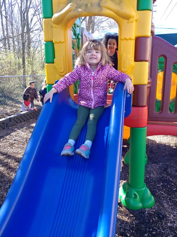 Child sitting on a blue slide on a playground
