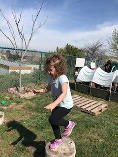 Child balancing on a tree stump outdoors