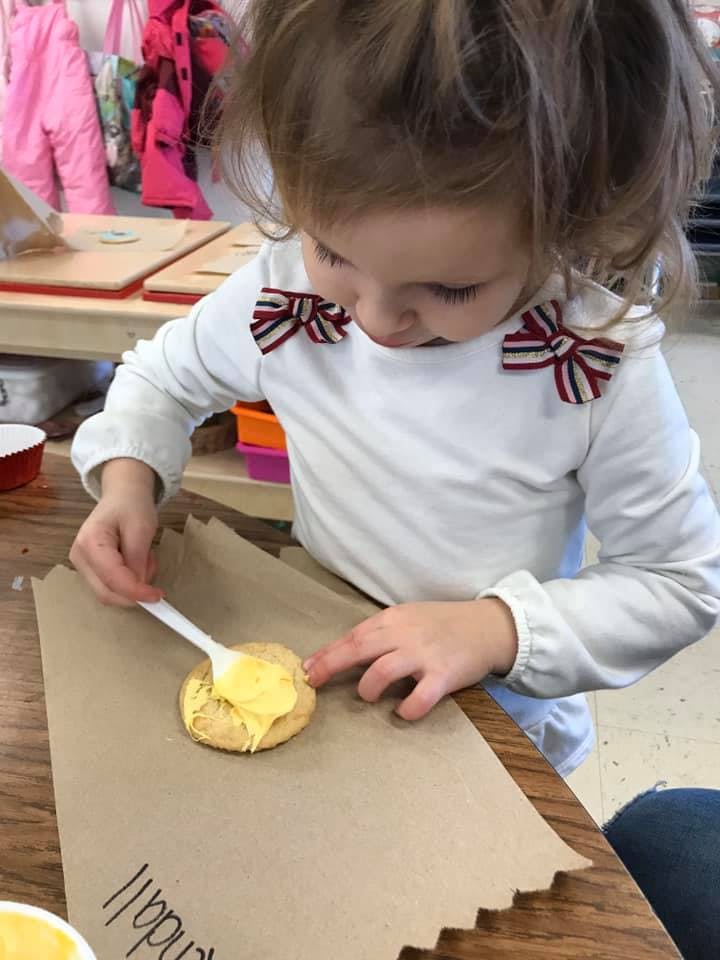 Child spreading frosting on a cookie with a spoon