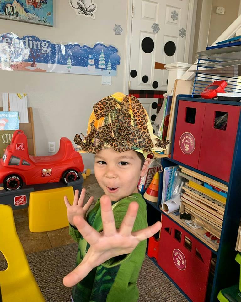 Child in a leopard print hat holding hands up