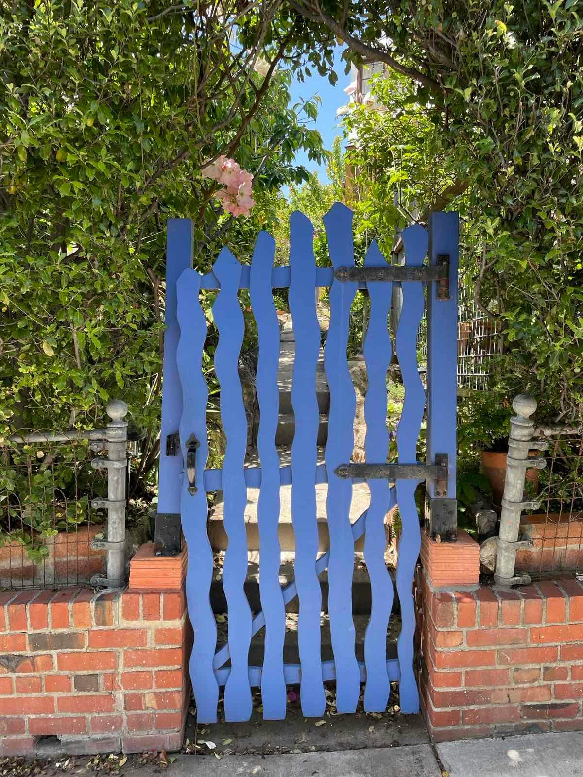 Blue wooden gate with wavy pickets set in a brick wall