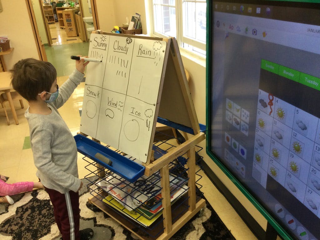 Child writing on a whiteboard in a classroom