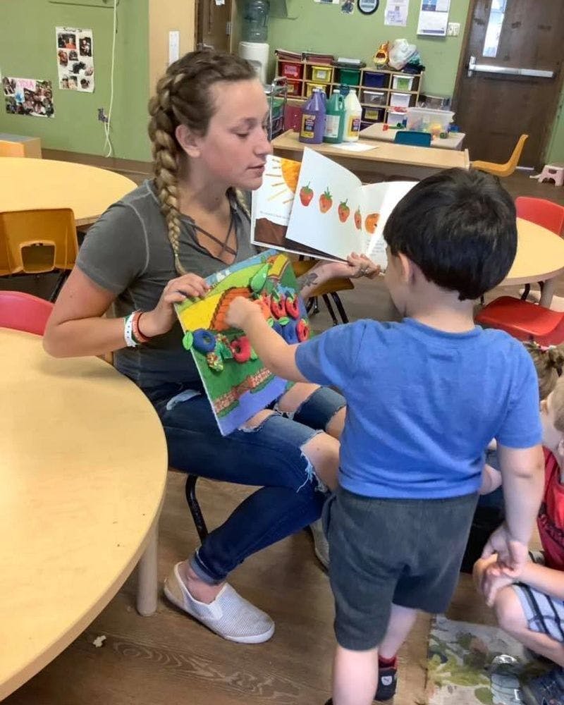 Person reading a book to a child in a classroom