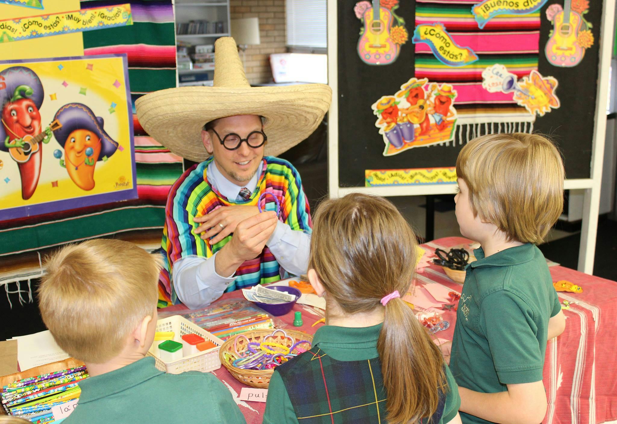Person in sombrero and colorful poncho interacting with three children