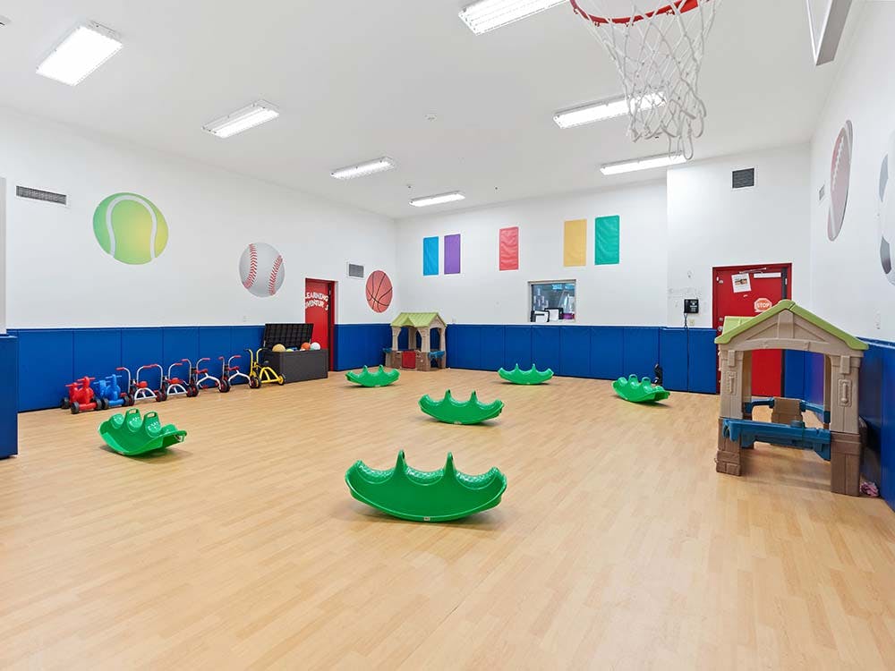 Empty children's playroom with ride-on toys, playhouses, and rocking animals