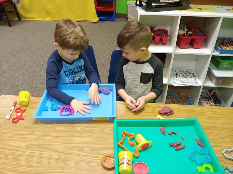 Two children playing with modeling clay at a table