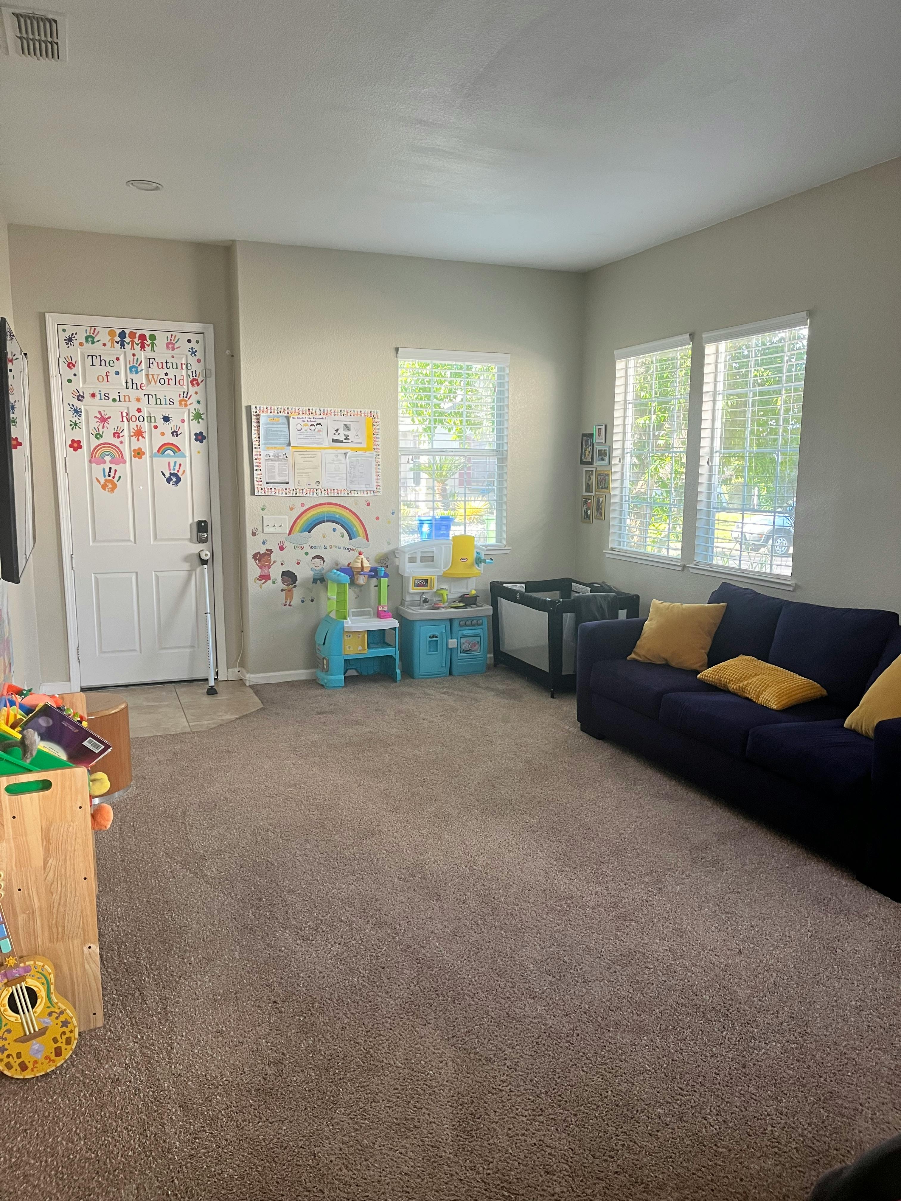 Living room with a blue couch, windows, and child's play area