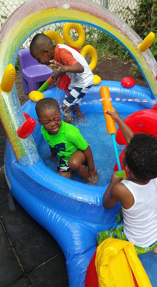 Three children playing in an inflatable pool with water toys