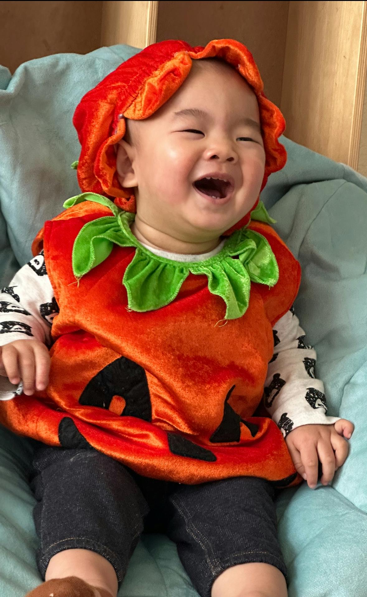 Child in a pumpkin costume laughing