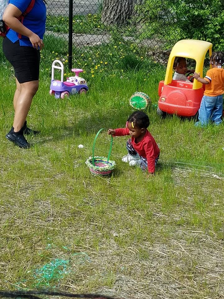 Child with a basket on grass, another child in a toy car