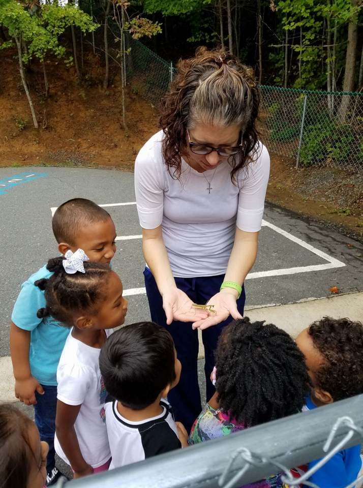 Person showing small object in hands to group of children