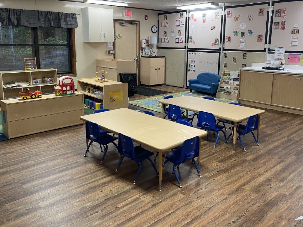 Classroom with child-sized tables and chairs, play area, and activity boards