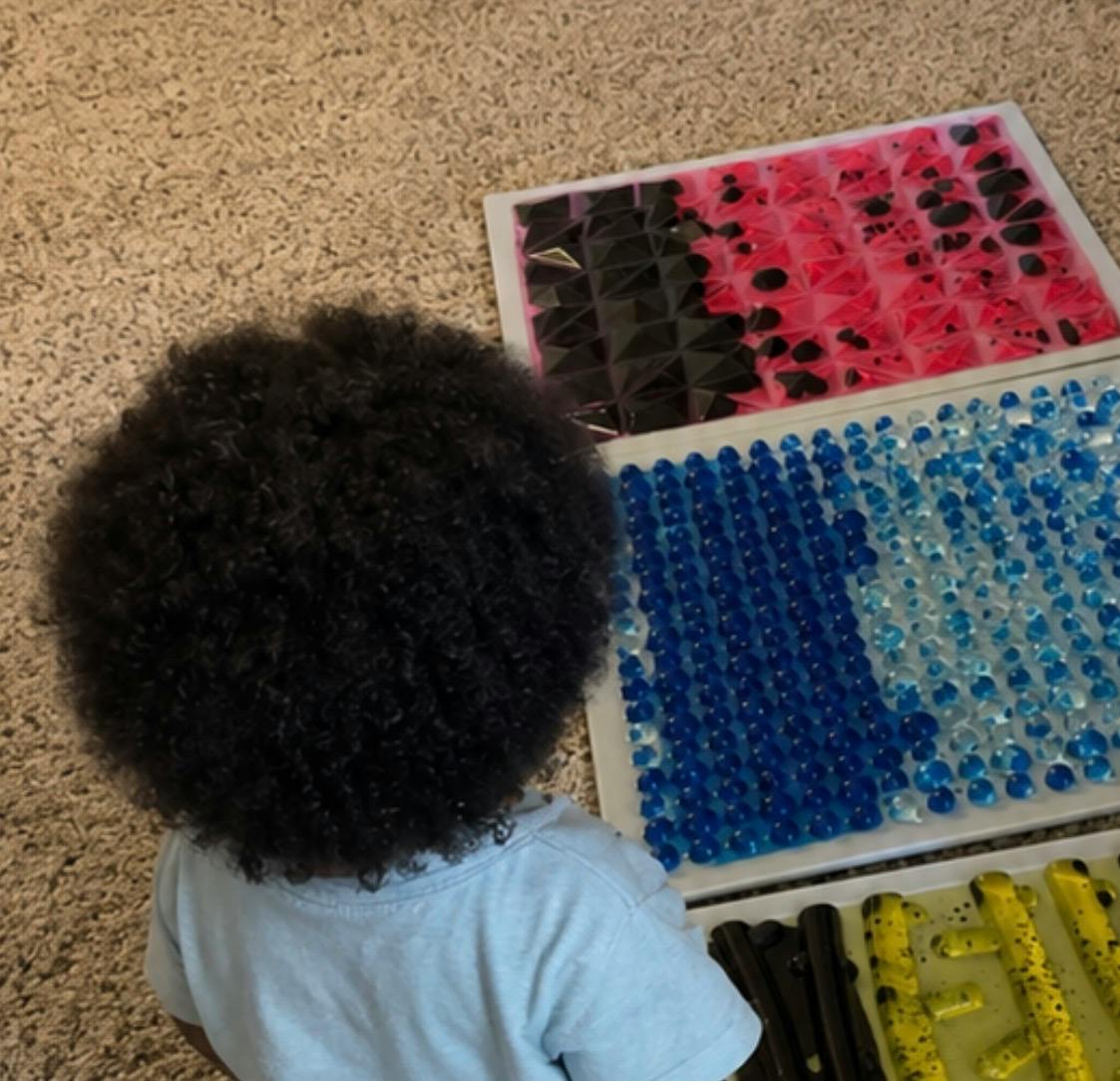 Child looking at trays of textured sensory items
