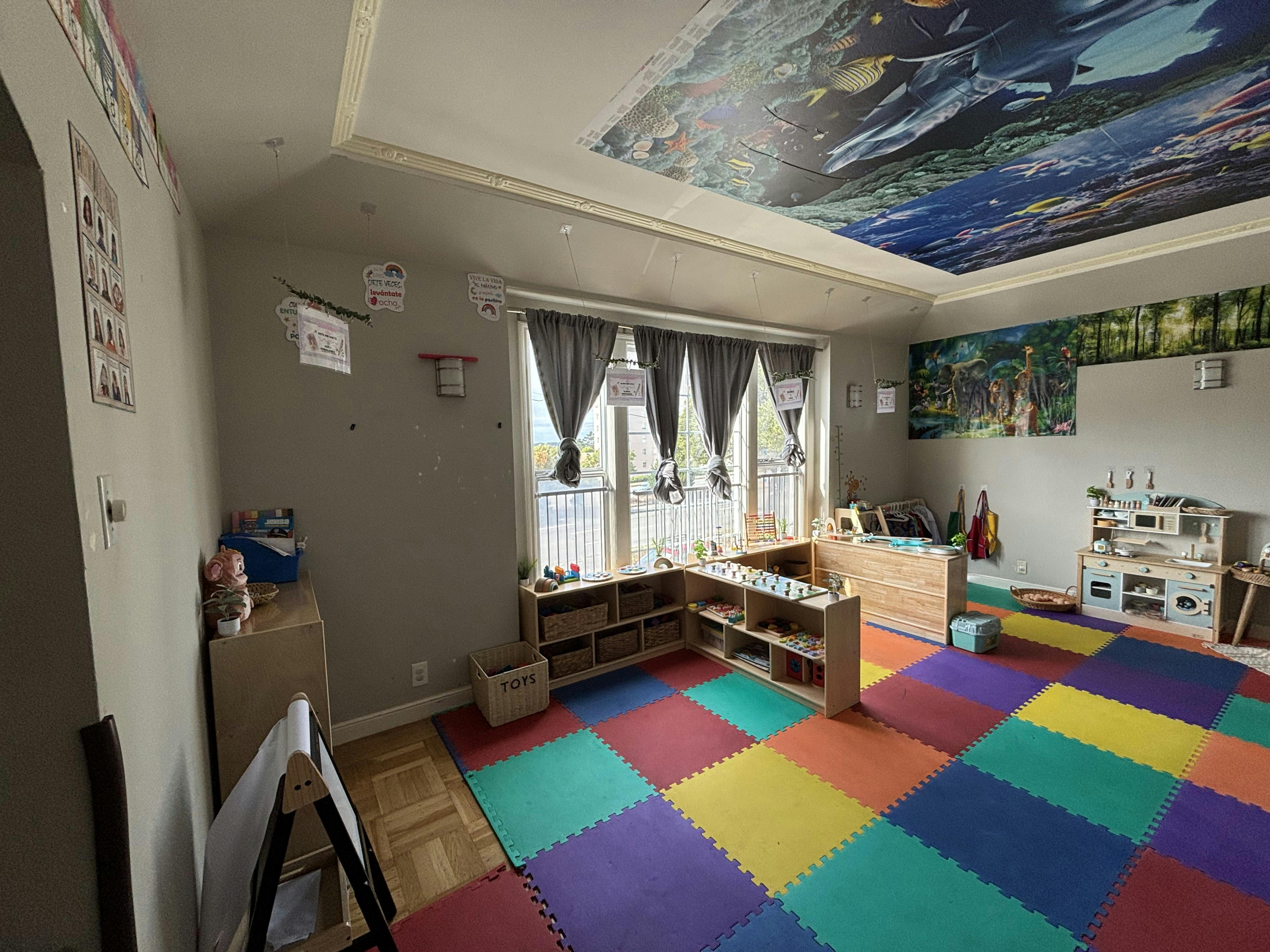 Playroom with colorful floor mats, window, and ceiling mural